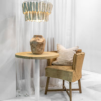 Styled scene featuring the Uniqwa Collections Brunswick Bar Table with a white base and reclaimed teak top, paired with a tan slipcover armchair and artisanal décor under a textured pendant light