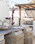 Cala Outdoor Dining Chairs with woven detailing and neutral cushions styled around a rustic timber table in an outdoor entertaining area.