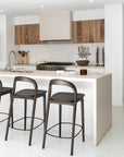 Loki Barstools in Espresso viewed on an angle at a neutral kitchen island, showcasing their curved backs and slender timber frames