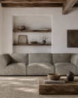 Manson modular sofa in earthy grey styled in a rustic lounge with timber shelving textured walls and natural woven flooring