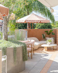 Oasis sofa with Maaru planter styled on a sunlit rooftop bar terrace with soft neutral tones textured seating and lush tropical greenery creating a relaxed outdoor setting