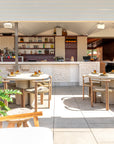 Salalah dining table arranged across a rooftop bar setting with woven chairs stone textures and lush greenery creating a relaxed open air dining atmosphere