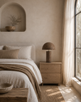 Large Samrah table lamp with a textured brown paper mache base and dome shade styled on a timber bedside table in a warm and tranquil bedroom.