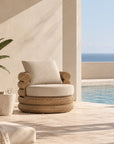 Satori Swivel Chair with woven natural finish and neutral cushions styled beside a swimming pool.