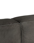 Close-up of a dark gray textured leather or sofa corner with visible stitching and a clean white background.
