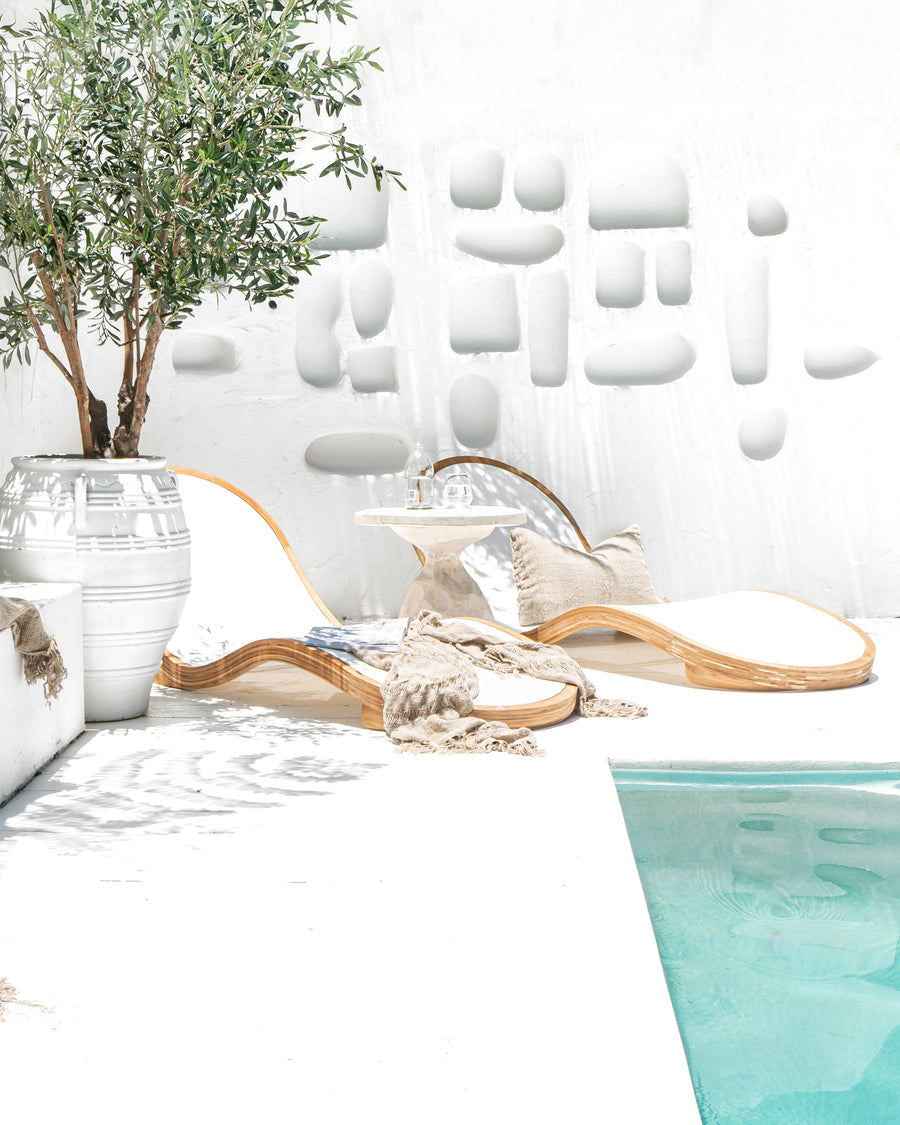 Uniqwa Collections Serene outdoor furniture Modern luxury poolside lounge chairs with curved teak wooden frame, paired with a sculpted side table for a Mediterranean-inspired retreat. Perfect for stylish, high-end outdoor living.