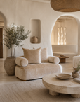 Soneva sofa in Dolce with soft curved lines and plush upholstery styled in a light filled Mediterranean inspired living room with natural textures and sculptural furnishings.