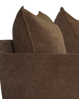 Close-up of a brown upholstered sofa arm with matching brown throw pillows against a white background.