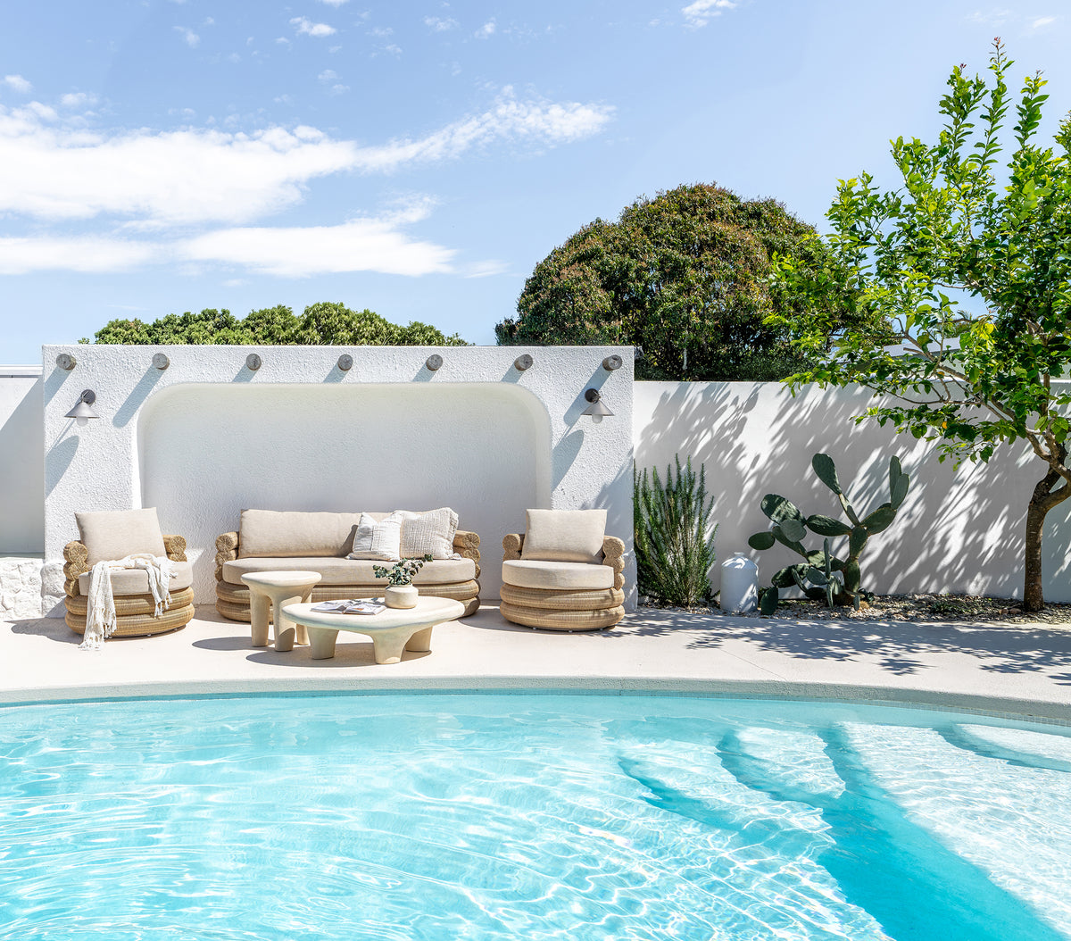 Bedu and Satori Collections styled in a relaxed poolside outdoor setting with woven seating and sculptural tables.
