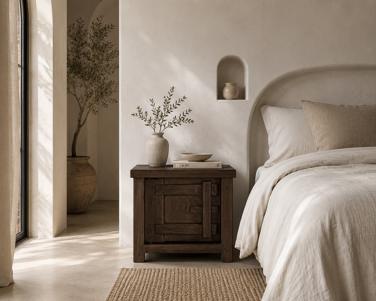 Bulu Bedside in Chocolate Elm styled beside a neutral bed in a Mediterranean inspired bedroom with warm natural textures and soft sunlight.