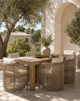 Cala Dining Chair with a curved woven frame and neutral cushions, styled around a timber table in a Mediterranean-inspired outdoor dining setting