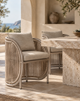 Cala Dining Chair with curved woven detailing and neutral upholstery, styled in a Mediterranean-inspired dining setting.