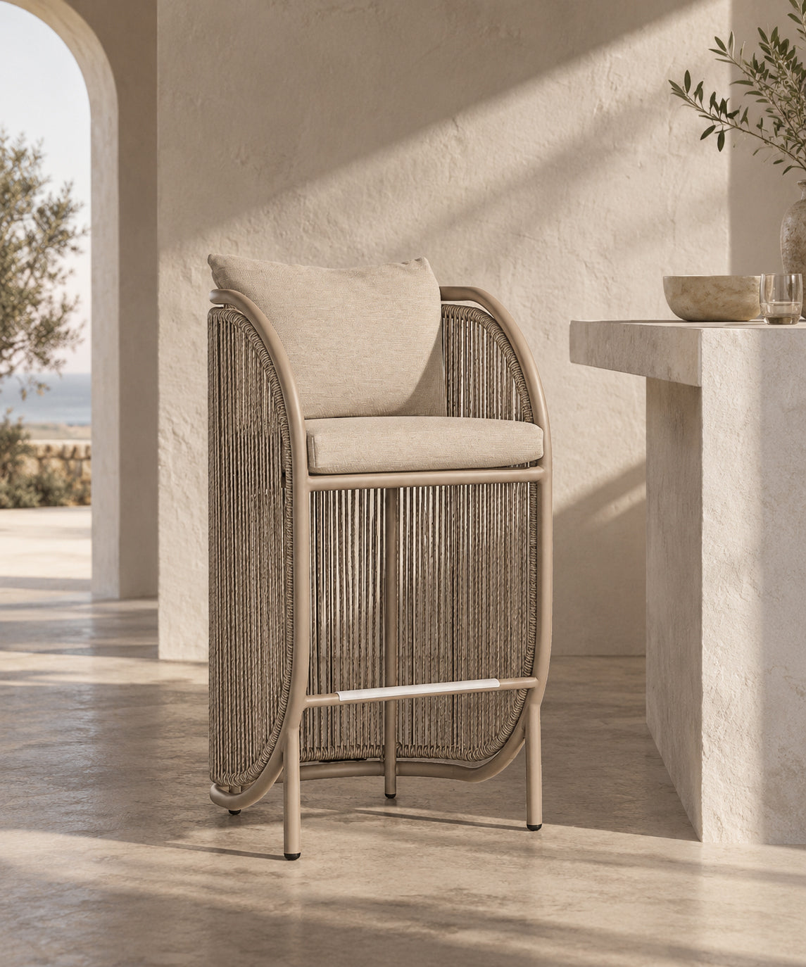 Cala Outdoor Bar Chair with woven detailing and neutral cushions styled in a warm outdoor entertaining space.
