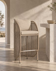 Cala Outdoor Bar Chair with woven detailing and neutral cushions styled in a warm outdoor entertaining space.