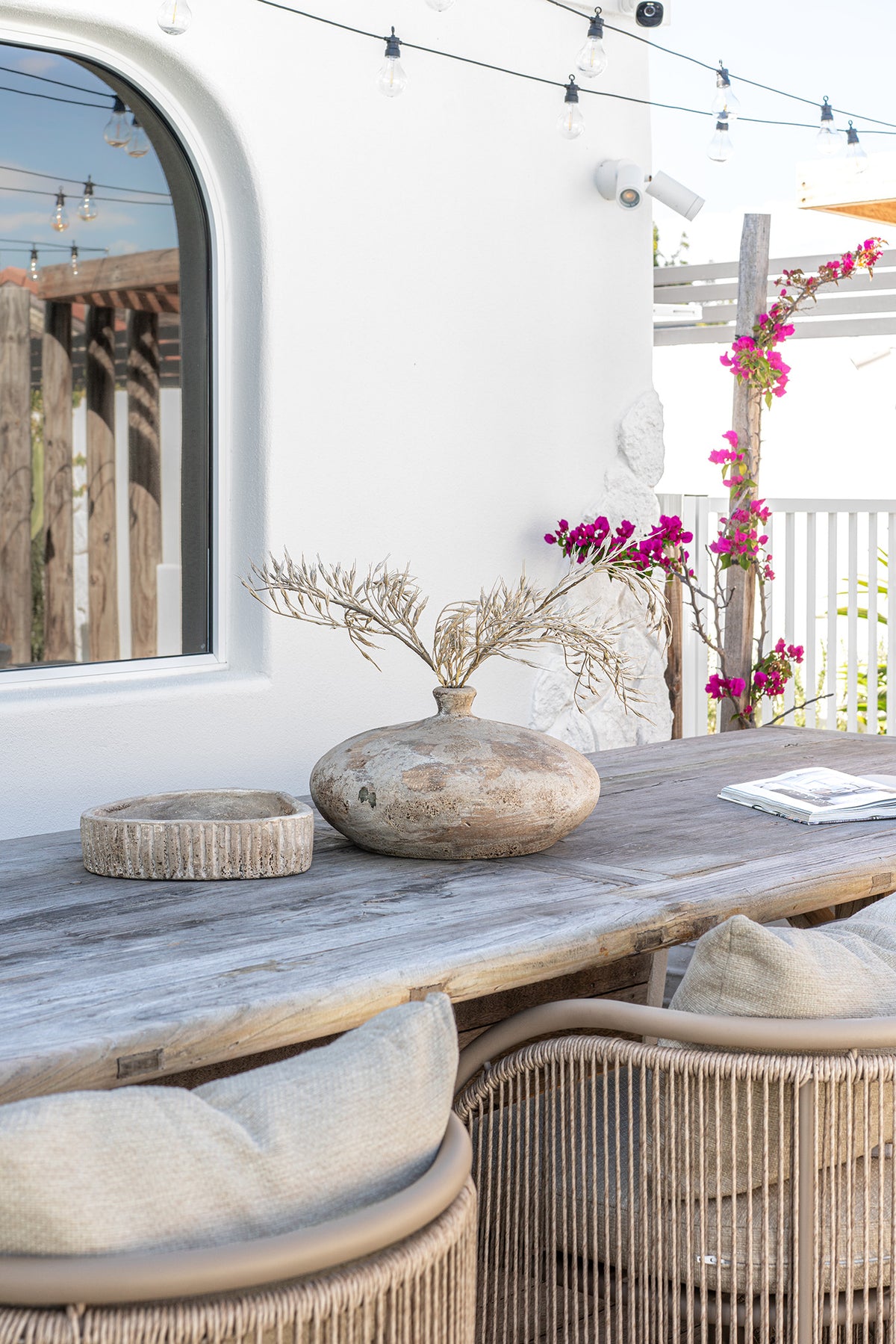 Cala Outdoor Dining Chairs with woven detailing and neutral cushions styled around a rustic timber outdoor dining table.