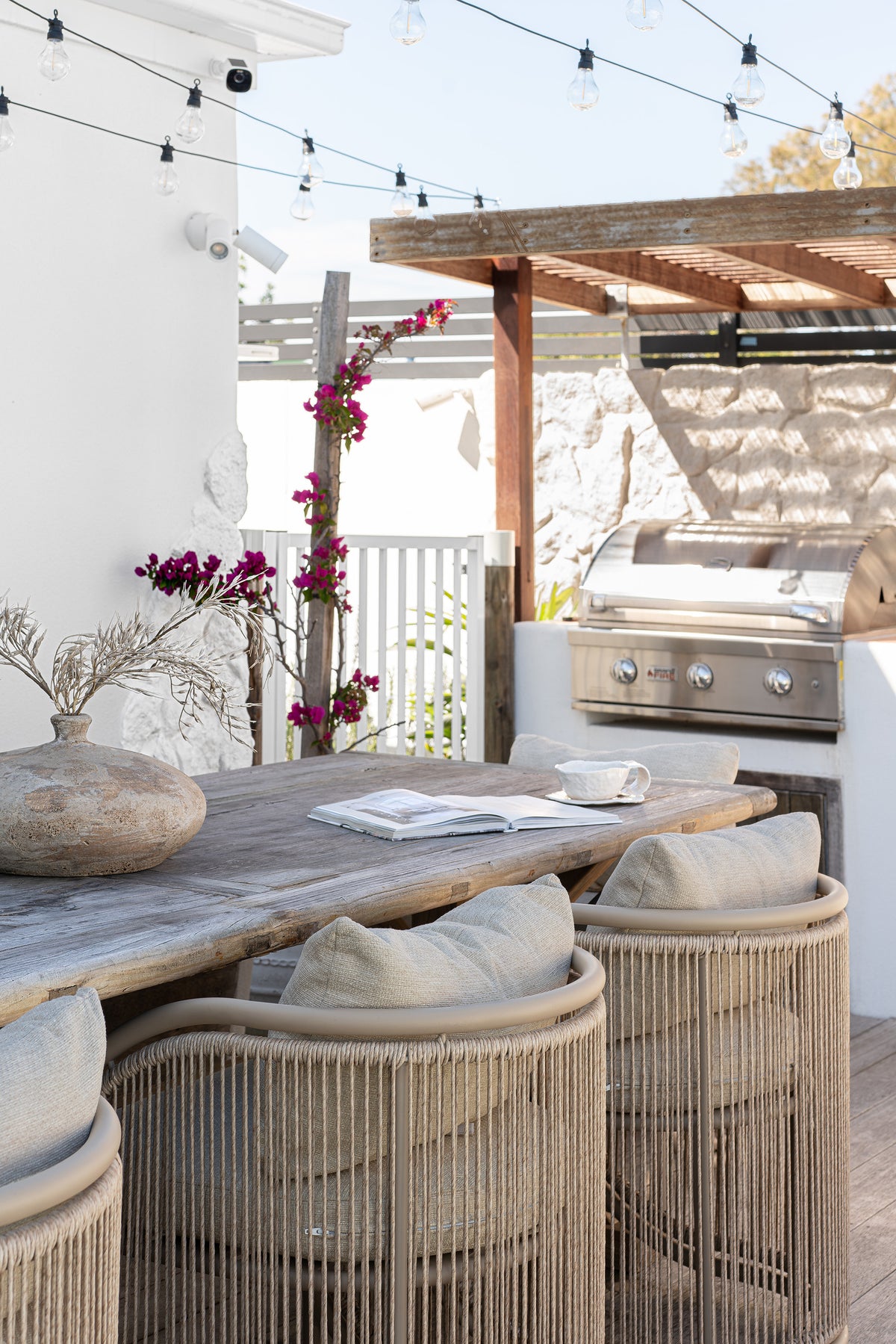 Cala Outdoor Dining Chairs with woven detailing and neutral cushions styled around a rustic timber table in an outdoor entertaining area.
