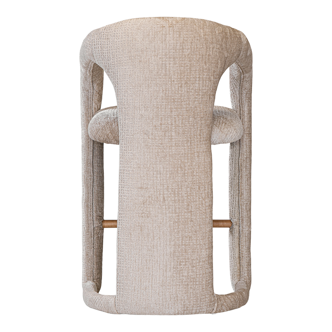 Fikile bar chair in sand mirage upholstery with a sculptural curved frame and integrated timber footrest detail.