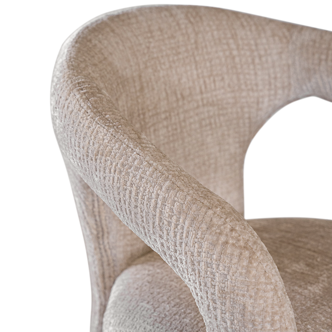 Fikile bar chair in sand mirage upholstery with a sculptural curved frame and integrated timber footrest detail.