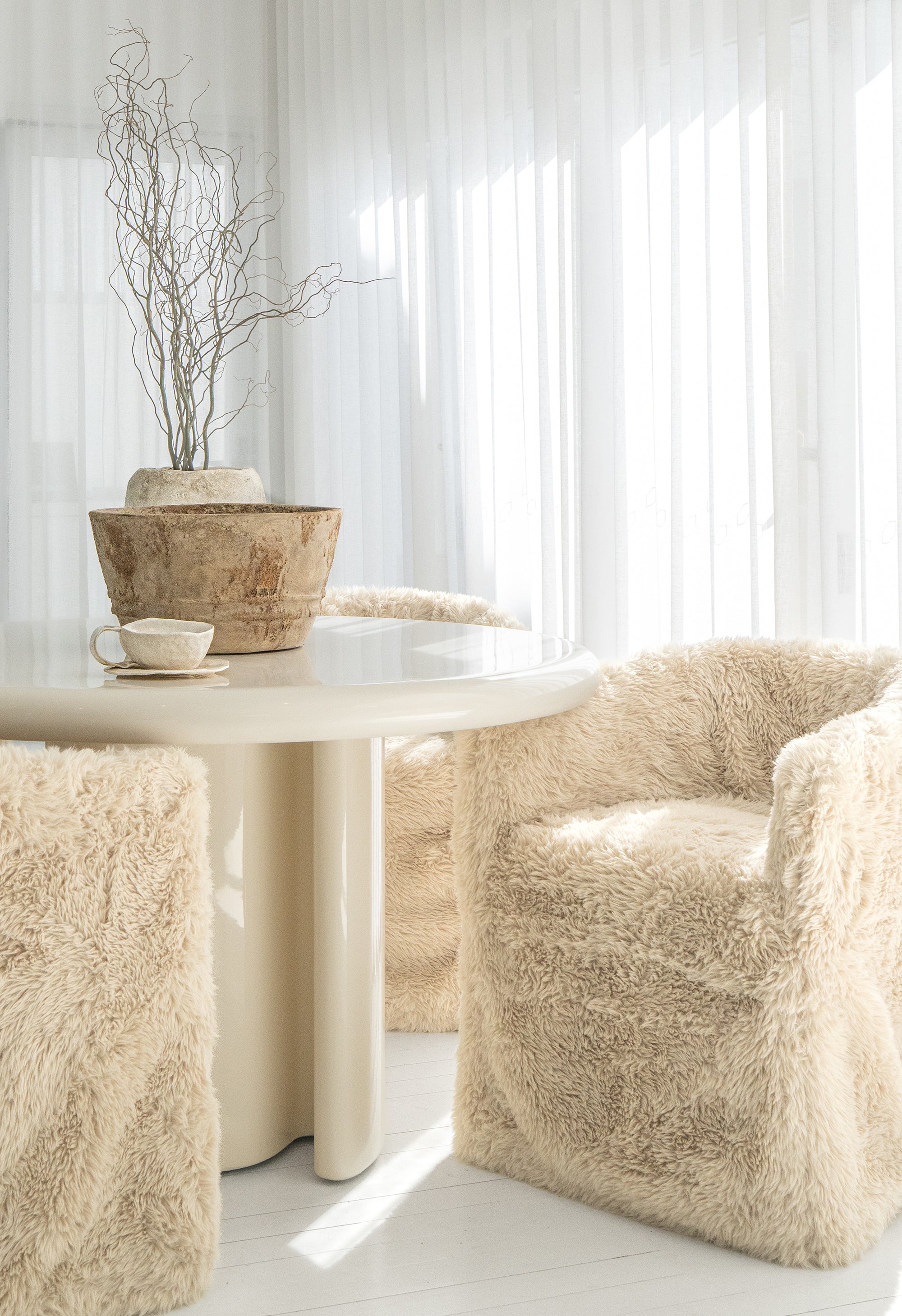 Hamilton Dining Chairs in Fur Luxe surround the Salalah Dining Table in High Gloss Vanilla, styled with sculptural planters and a Bloom Mug