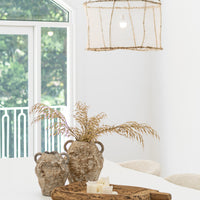 Uniqwa Colletions handwoven net pendant light hanging above a white dining table styled with Ukoko Vase, and a rustic carved naga wooden tray with candles, creating a natural and textural interior aesthetic.