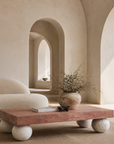 Jewel coffee table with a warm stone top and sculptural travertine sphere legs styled in a light filled Mediterranean inspired living room.