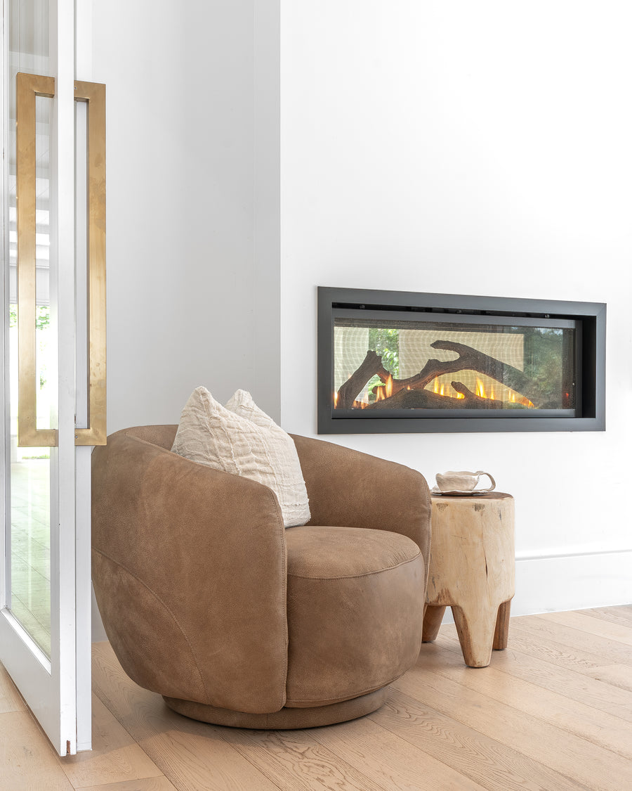 Leather swivel chair styled with a raw side table beside a modern fireplace, creating a warm and inviting corner with organic textures and natural elements