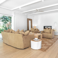 Leather sofa and armchairs styled with a reclaimed wood coffee table and textured cushions, complemented by a woven jute rug, sculptural side table, and a fireplace in a modern organic living room