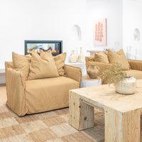 Leather sofa with oversized cushions styled around a reclaimed wood coffee table, complemented by a textured woven rug, ceramic vases, and a modern fireplace in a warm, organic living space