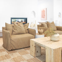 Leather sofa with oversized cushions styled around a reclaimed wood coffee table, complemented by a textured woven rug, ceramic vases, and a modern fireplace in a warm, organic living space