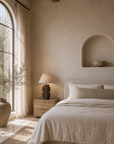 Liwa table lamp with a sculptural textured base and paper mache shade styled on a timber bedside table in a warm natural bedroom.