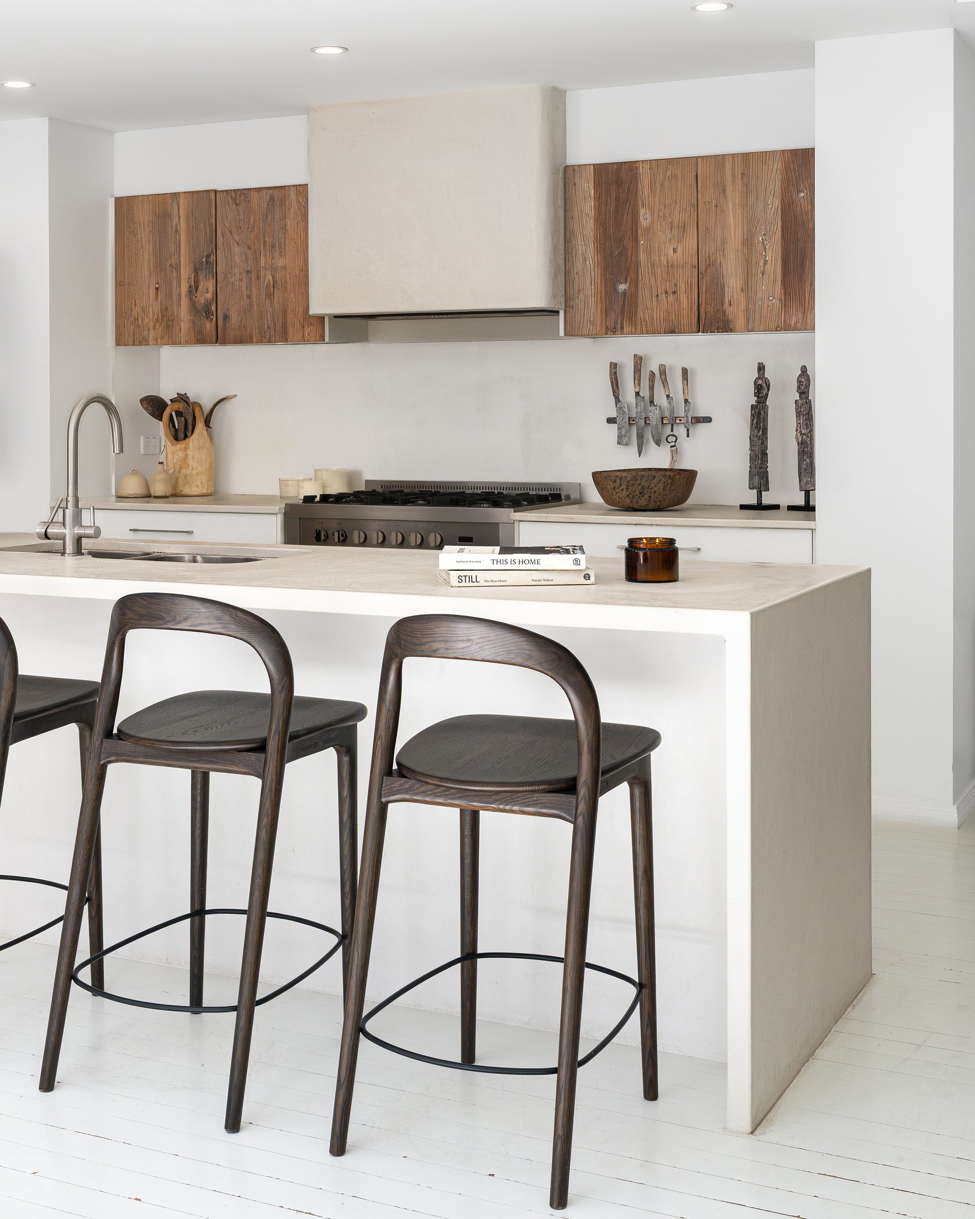 Loki Barstools in Espresso viewed on an angle at a neutral kitchen island, showcasing their curved backs and slender timber frames