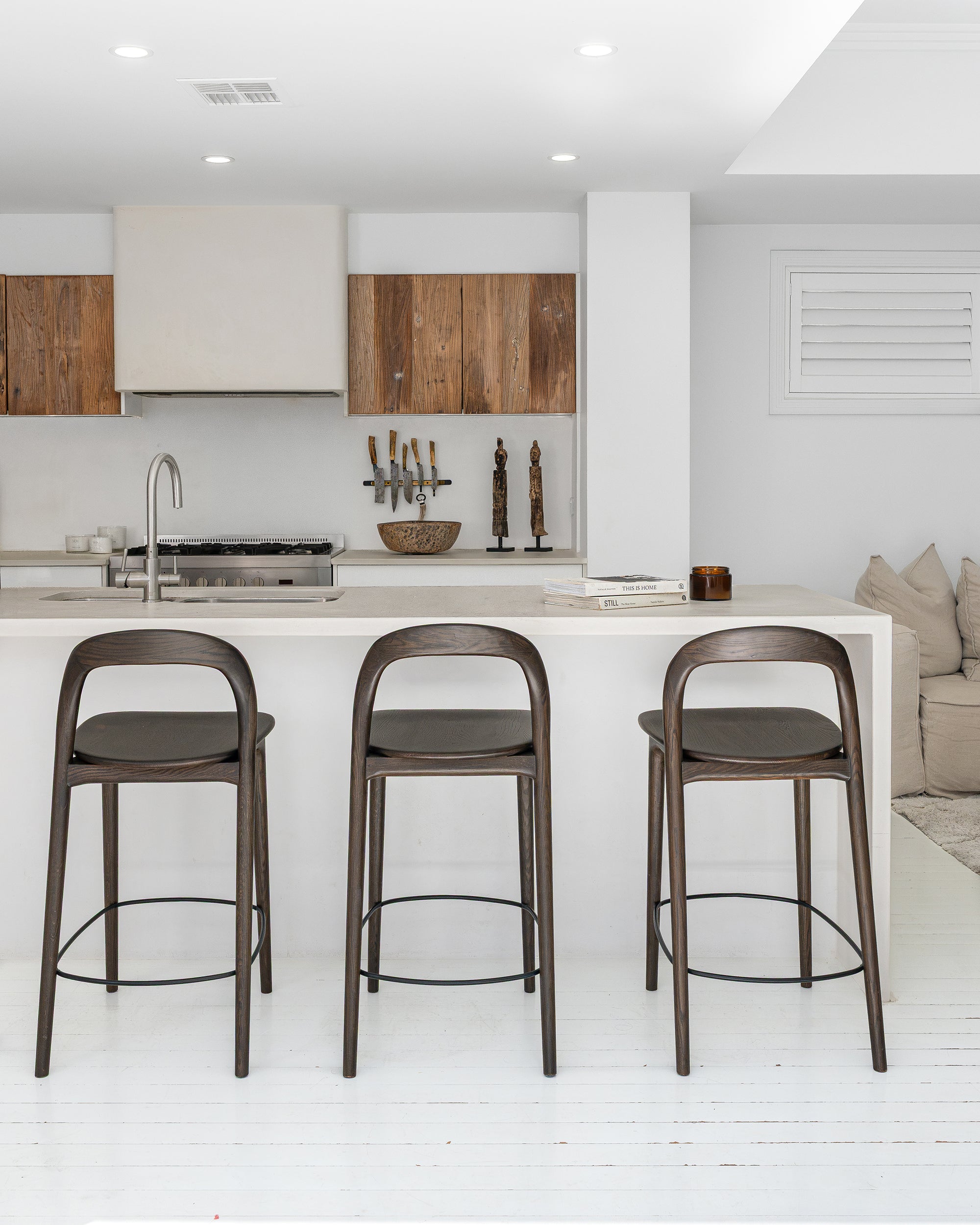 Loki Barstools in Espresso shown closer to the kitchen island, highlighting the sculptural curved back and streamlined timber frame.
