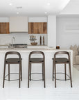 Loki Barstools in Espresso shown closer to the kitchen island, highlighting the sculptural curved back and streamlined timber frame.