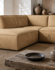 Manson modular sofa in cashew leather styled in a rustic living room with timber ceiling beams textured decor and warm natural tones