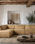 Manson modular sofa in cashew leather styled in a rustic living room with timber ceiling beams textured decor and warm natural tones