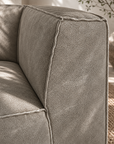 Manson modular sofa in earthy grey styled in a rustic lounge with timber shelving textured walls and natural woven flooring