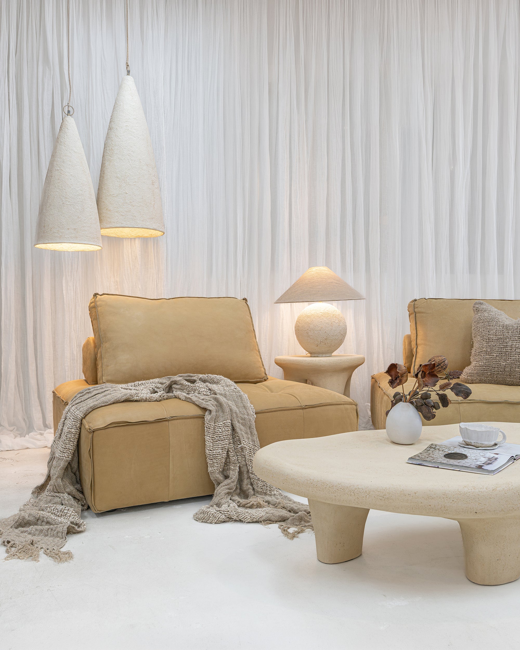 Bedu Coffee Table with a rounded sculptural form, styled with Maui Sofa seating, Sabi Table Lamp and Senah Pendants.