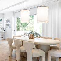 Stone dining table paired with sculptural boucle dining chairs, illuminated by oversized linen pendant lights, creating an inviting and textural modern dining space with natural light and organic decor.