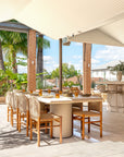 Mukalla dining table styled in an open rooftop bar setting with woven dining chairs warm brick columns and soft natural light creating a relaxed outdoor dining space