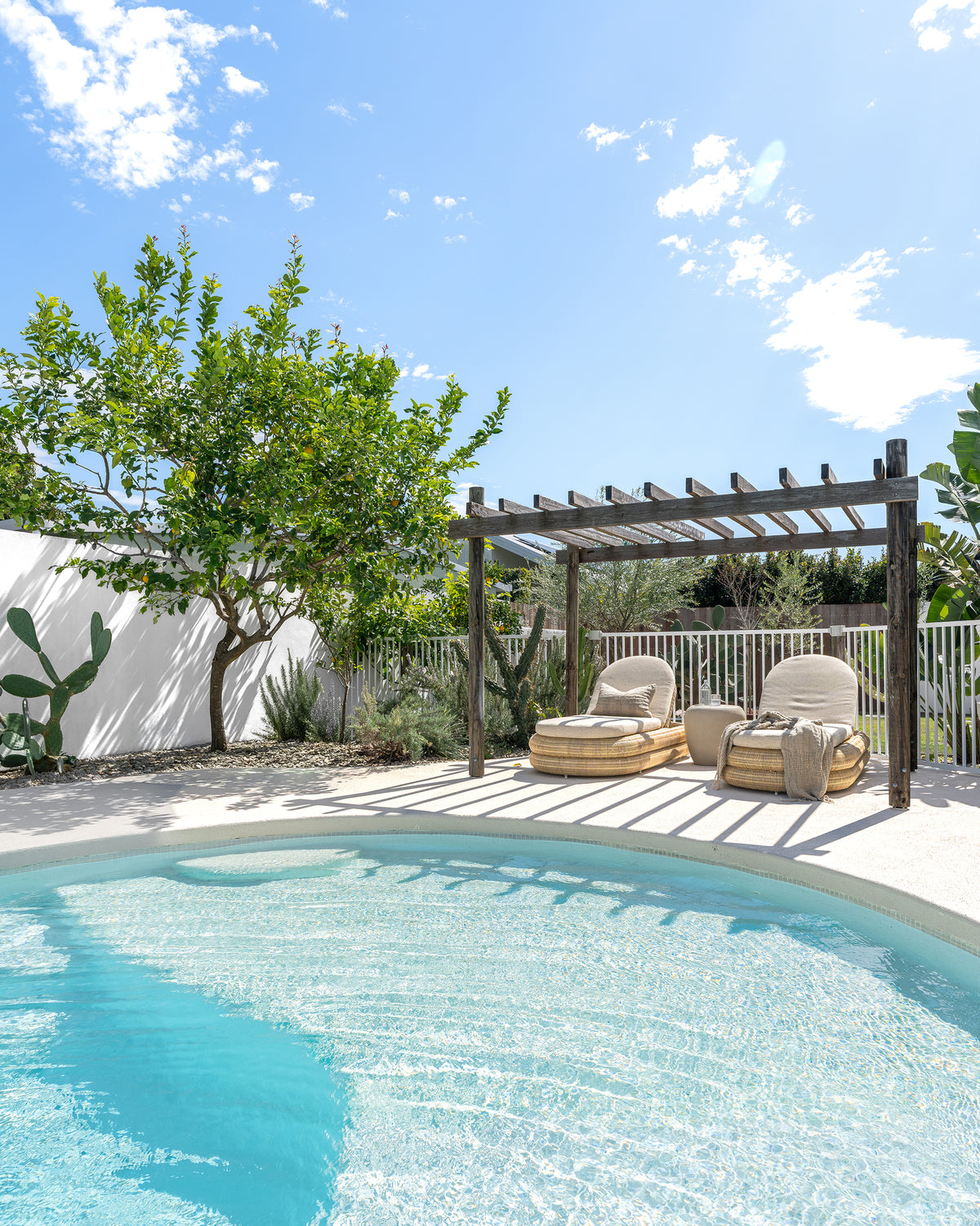 Nomara Side Table in Driftstone styled between Satori Outdoor Sun Loungers in a relaxed poolside setting.