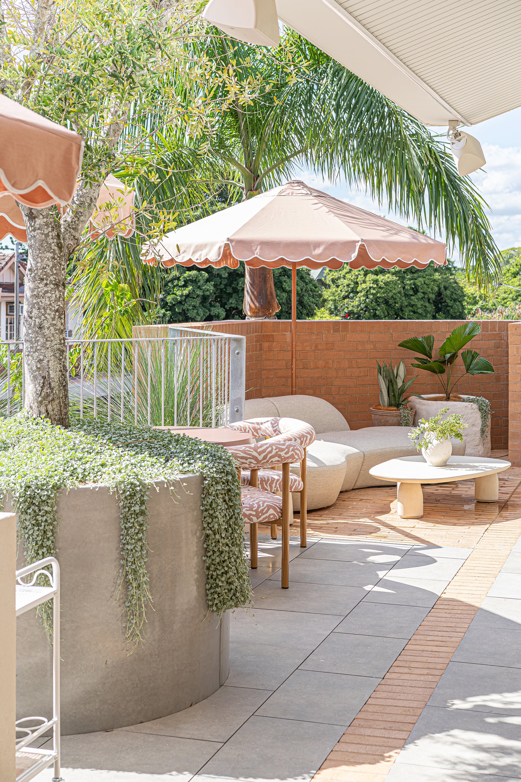 Oasis sofa with Maaru planter styled on a sunlit rooftop bar terrace with soft neutral tones textured seating and lush tropical greenery creating a relaxed outdoor setting