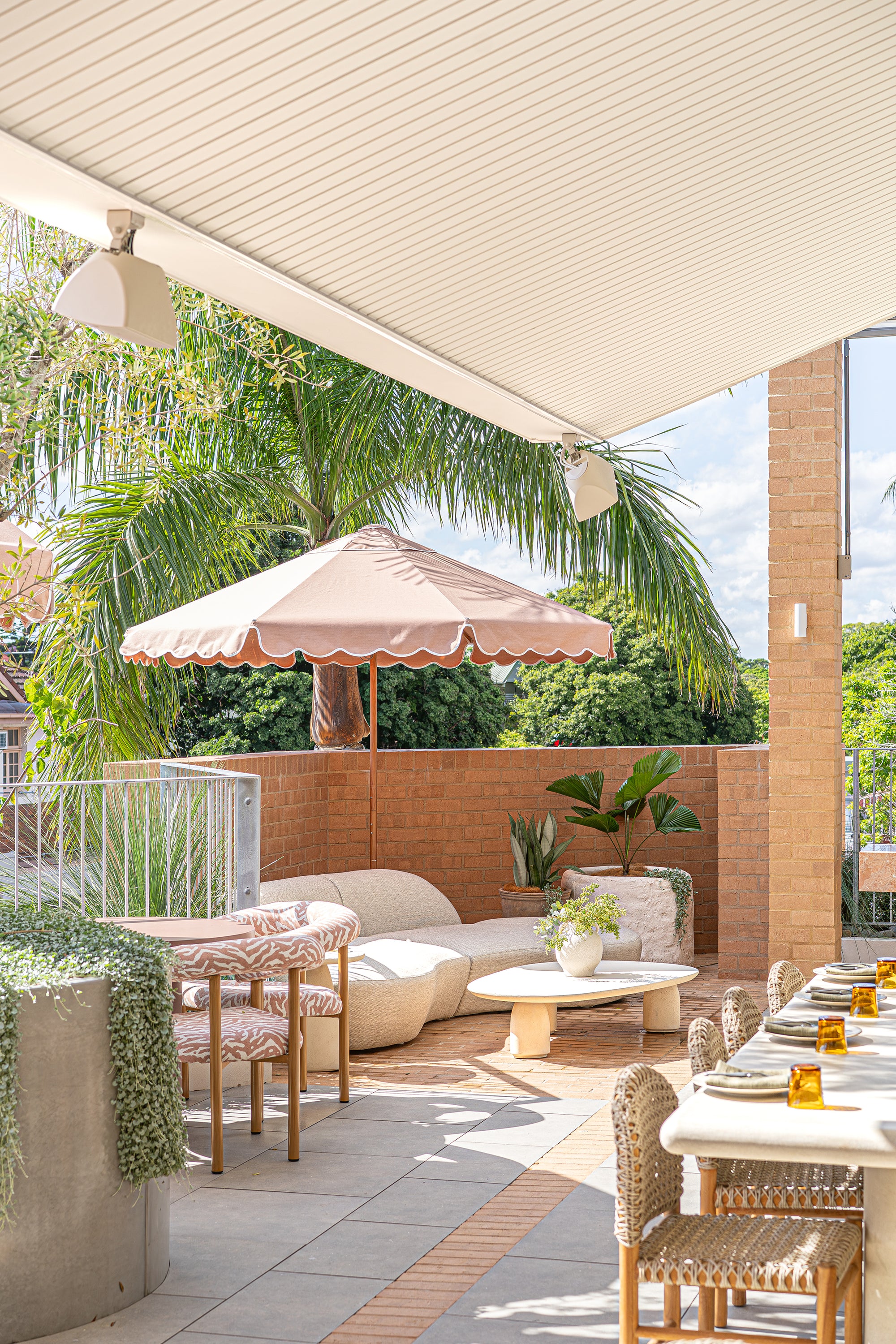 Oasis sofa with Maaru planter styled on a sunlit rooftop bar terrace with soft neutral tones textured seating and lush tropical greenery creating a relaxed outdoor setting