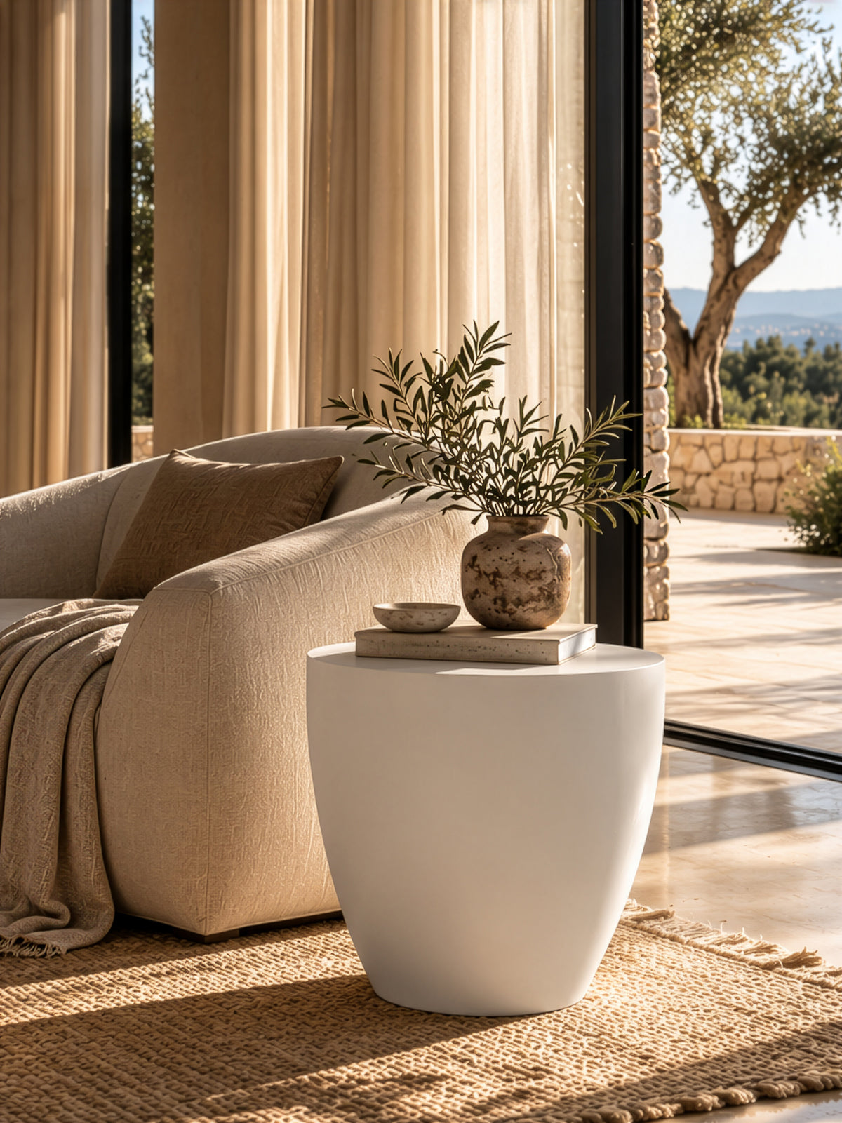 Palm Cut Side Table in white resin with a sculptural tapered form, styled beside a curved sofa in a neutral living room with natural textures.