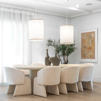 Elegant dining room featuring a sculptural plaster dining table surrounded by upholstered dining chairs in a neutral palette, complemented by soft linen pendant lights and artisanal decor