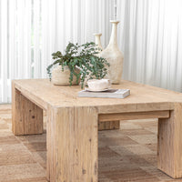 Uniqwa Collections a rustic reclaimed wood coffee table styled with textured ceramic vases, lush greenery, a sculptural cup, and a design magazine, set against soft white curtains for a tranquil and organic living space