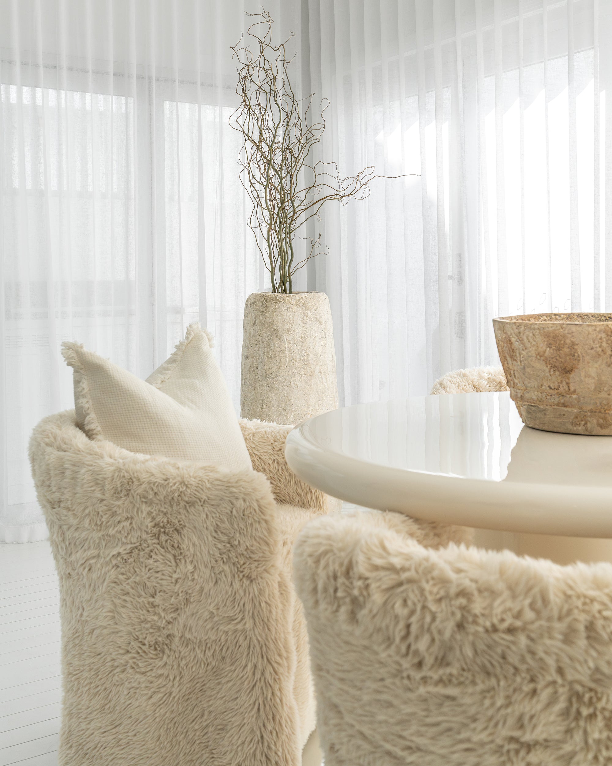 Hamilton Dining Chairs in Fur Luxe beside the Salalah Dining Table in High Gloss Vanilla, with Nusa Palm and Muhle planters completing the setting