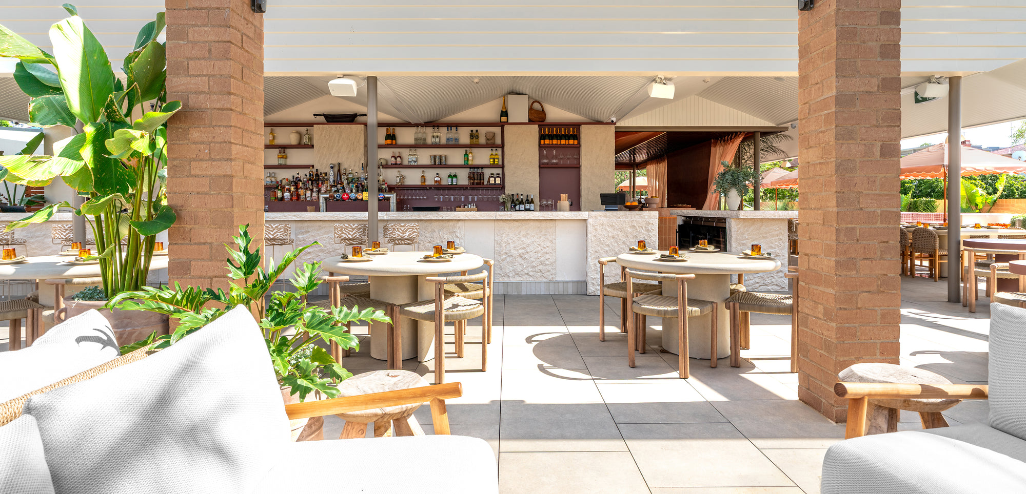 Salalah dining table arranged across a rooftop bar setting with woven chairs stone textures and lush greenery creating a relaxed open air dining atmosphere