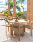 Salalah dining table styled on a rooftop terrace with woven chairs soft neutral finishes and surrounding tropical greenery creating a warm open air dining setting