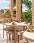 Salalah dining table styled on a rooftop terrace with woven chairs soft neutral finishes and surrounding tropical greenery creating a warm open air dining setting