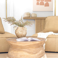 Solid timber coffee table styled with a Naga Vase filled with dried foliage, positioned between suede lounges in a warm, earthy-toned living space with organic decor elements